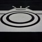 A black and white graphic of a camera painted on asphalt.
