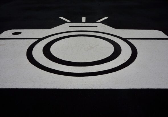 A black and white graphic of a camera painted on asphalt.