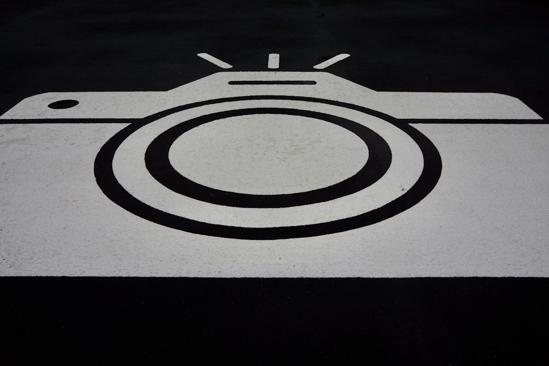 A black and white graphic of a camera painted on asphalt.
